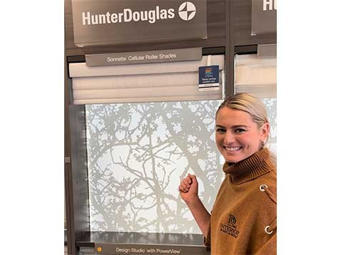 A woman in a turtle-neck sweater showing off a Hunter Douglas display